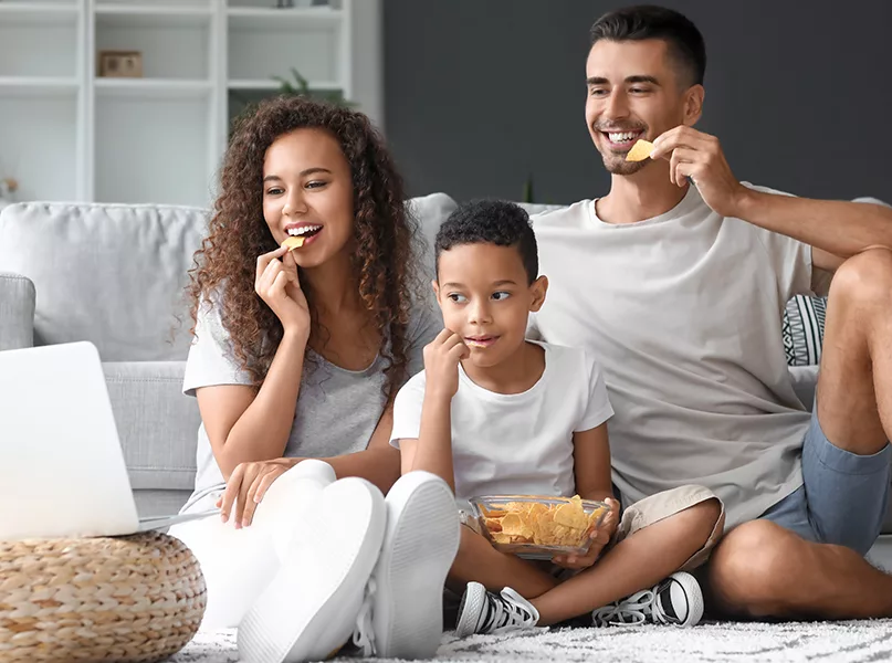 Family with laptop eating chips at home