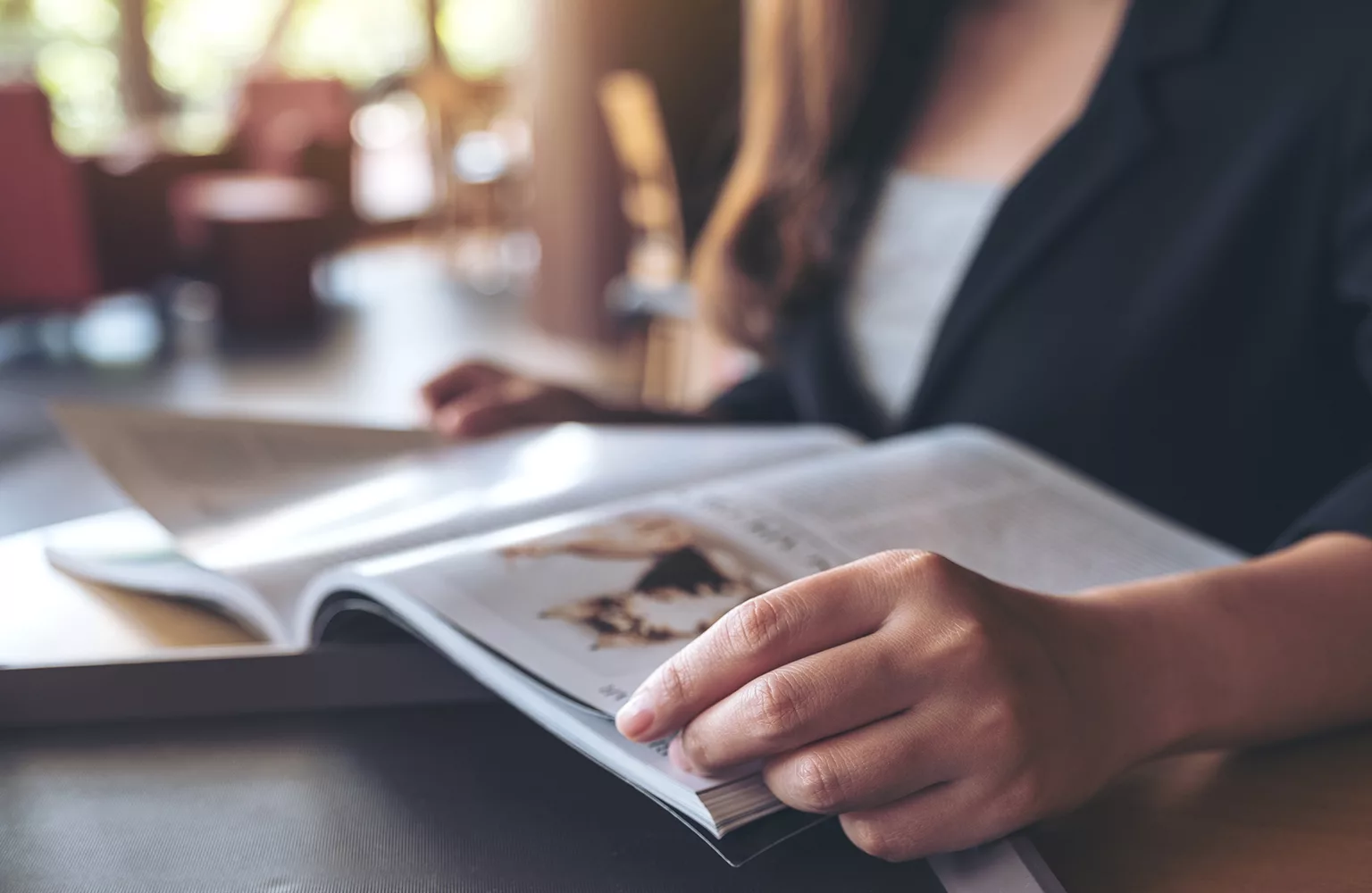 Closeup image of a business woman reading a book in modern cafe
