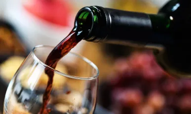 Red wine pouring into a wine glass at a tasting